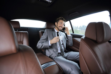 Fototapeta na wymiar Happy young businessman using mobile phone in back seat of car