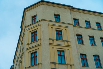 Fototapeta na wymiar yellow corner house with blue windows