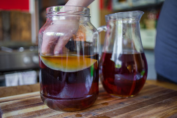 close up image of the step by step way to prepare kombucha tea using a live bacteria culture, scobie and black tea in a real life kitchen
