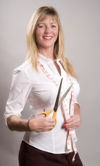 A female tailor holding scissors and a tape measure