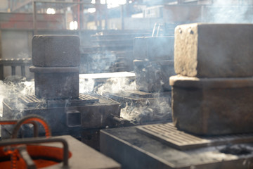 Naklejka na ściany i meble steam rises as cast iron cools in a foundry
