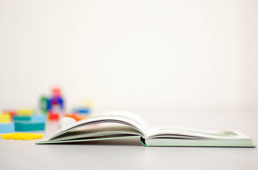open book in the foreground and toys in the background, the concept of learning, place for text
