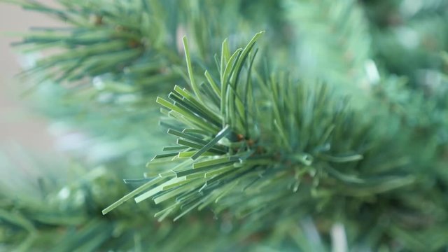 Panning on Christmas tree artificial branches with green needles close-up 4K 2160p 30fps UltraHD footage - Realistic decorative spruce details shallow DOF slow pan 3840X2160 UHD video 