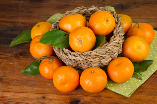 tangerine basket full with green napkin on old wooden background