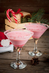 Traditional Christmas pink cocktail candy cane punch in glasses, decorated with shards of candy cane. Against box with gifts, the Christmas tree branches and decorations, copy space, selective focus 