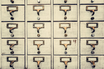Obraz premium Rows of little drawers with white empty tags in an old furniture module, Vintage style...