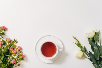Obraz na płótnie Canvas Flat lay of tea cup standing between flowers