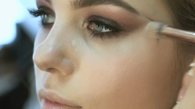Make-up artist applying eyelash makeup to model's eye. Close up view.