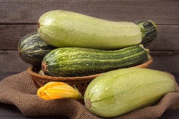 green zucchini and courgettes with a flower on sackcloth wooden background