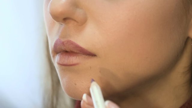 Makeup artist paints lips for girl. Professional make-up of model. Beautiful bride's makeup.