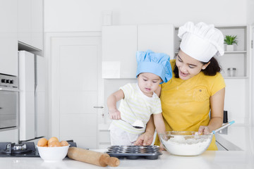 Cute child learns holding spoon with flour