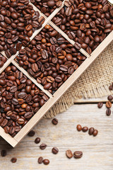 Roasted coffee beans in wooden basket on grey table