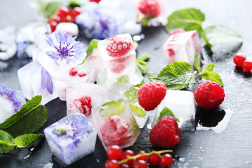 Ice cubes with raspberries and mint leaf on wooden table