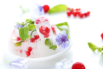 Ice cubes with raspberries and mint leaf on wooden table