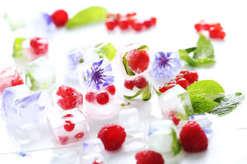 Ice cubes with raspberries and mint leaf on wooden table