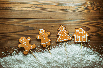 Christmas Background Theme. Ginger Men In The Snow Next To The House And Tree. Close-Up. Free Space For Text. Wooden Background. More Light. Vintage, Grunge Version. Top View.