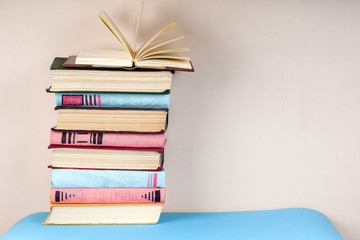 Fototapeta premium Open book, stack of colorful hardback books on light table. Back to school. Copy space for text