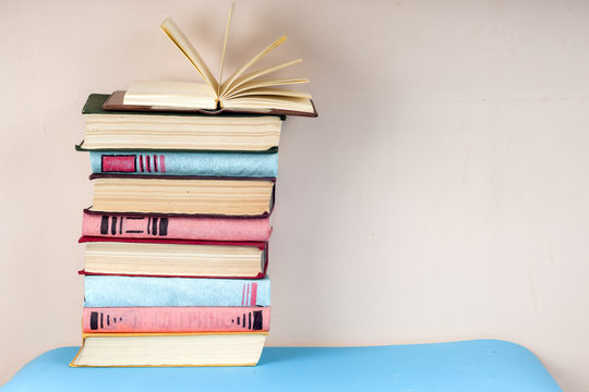 Open book, stack of colorful hardback books on light table. Back to school. Copy space for text