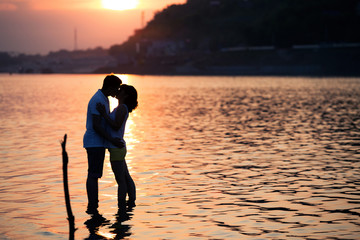 Romantic portrait of attractive couple in love hugs at the sunset . Against the backdrop of the sea...