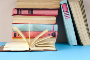 Open book, stack of colorful hardback books on light table. Back to school. Copy space for text