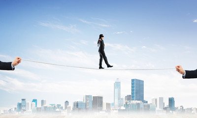 Business concept of risk support and assistance with man balancing on rope