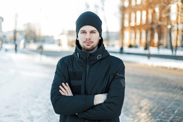Handsome young man in a knitted cap and a black jacket on a winter day © alones