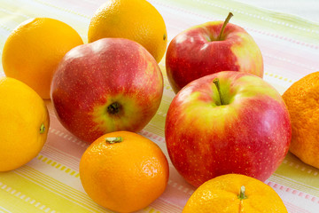 Red apples, oranges and tangerines on the table.