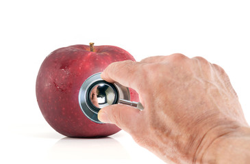 Stethoscope / View of hand holding stethoscope and red apple on white background. Health eating concept.