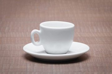 Clean and empty ceramic cup for espresso with saucer on wooden t