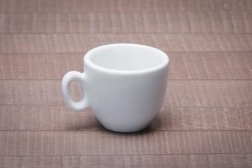 Clean and empty ceramic cup for espresso without saucer on woode