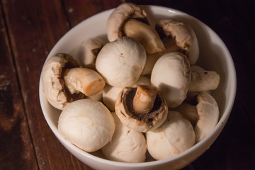 peeled mushrooms in a white bowl on wooden background