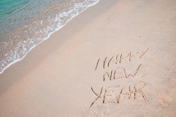 Happy New Year written in the white sand
