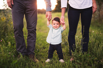 Cute baby boy holding his parent's hands