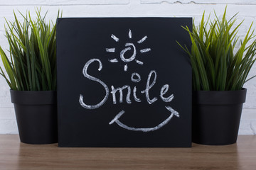 SMILE hand writing chalk text on black chalkboard