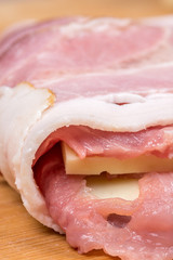 Side view of meat stuffed with yellow cheese and rolled in bacon