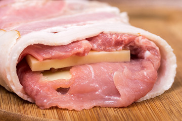 Side view of meat stuffed with yellow cheese and rolled in bacon