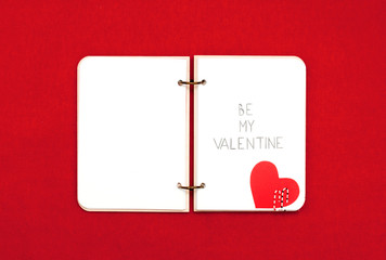 Opened blank notepad on red background. Valentine's hart