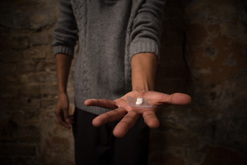 Drug addict man showing wheels. Closeup picture of man's hand with drugs on it. Man posing on...