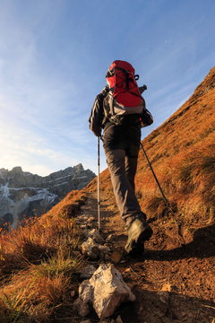 Hiker proceeds toward the group Forcella De Furcia at sunrise, Funes Valley, South Tyrol, Dolomites