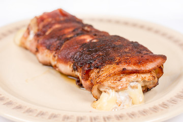 Melted yellow cheese in rolled steak with bacon