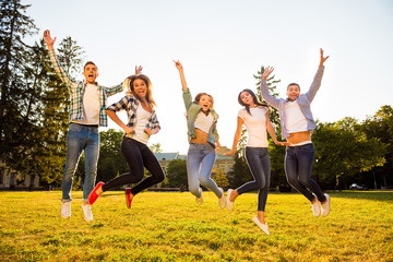 Five joyful boyfriends and girlfriends jumping and having fun on