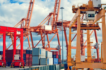 Industrial harbor, gantry cranes and container ship. Red and orange industrial cranes in port of Santa Cruz de Tenerife. Canary Islands, Spain.