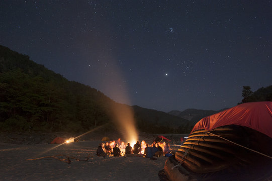 Sitting around a campfire next to the Karnali River during a rafting expedition in Nepal