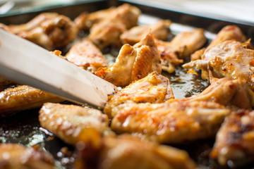 Cooking tongs holding bbq chicken wings