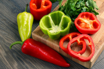 whole and sliced sweet peppers with herbs on a wooden board