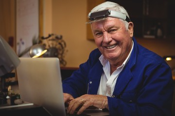 Horologist working on laptop in workshop