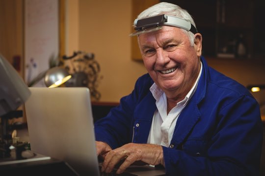 Horologist working on laptop in workshop