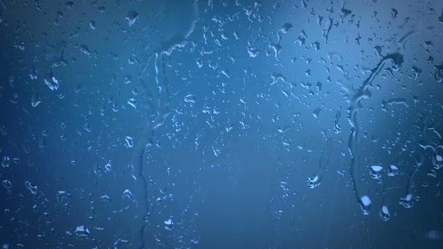 This is a close up photo of Blue Water Raindrops on Glass Window dripping down. This image will work well as a background for text and has a lot of copy space. There are no people in the photo.