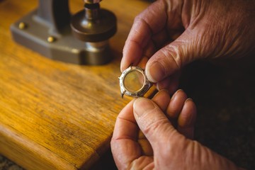 Horologist hand holding watch frame in workshop