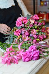 Woman florist tying the ribbon on the bouquet of roses